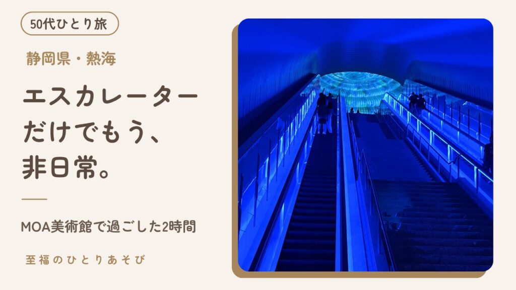 青い光のトンネルの奥に円形の万華鏡のプロジェクションマッピングが見えるMOA美術館のエスカレーター内観写真に、タイトルと「50代ひとり旅」のバッジを重ねた、MOA美術館訪問記のアイキャッチ画像
